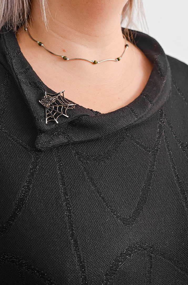 Чорна сукня з делікатним люрексовим мерехтінням і декоративною брошкою великих розмірів